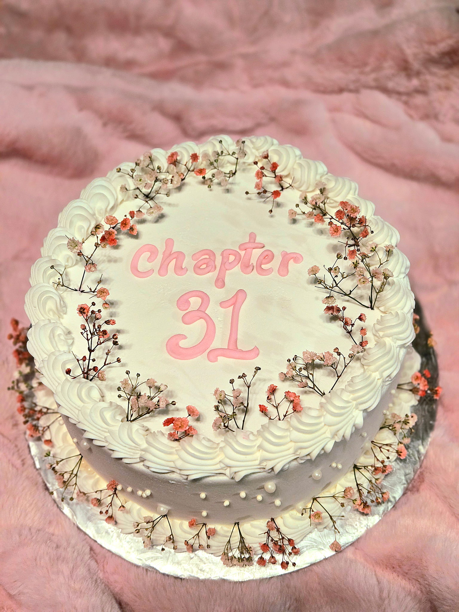 Round Chapter 31 birthday cake with whipped-buttercream rosettes and a dried baby's-breath wreath.