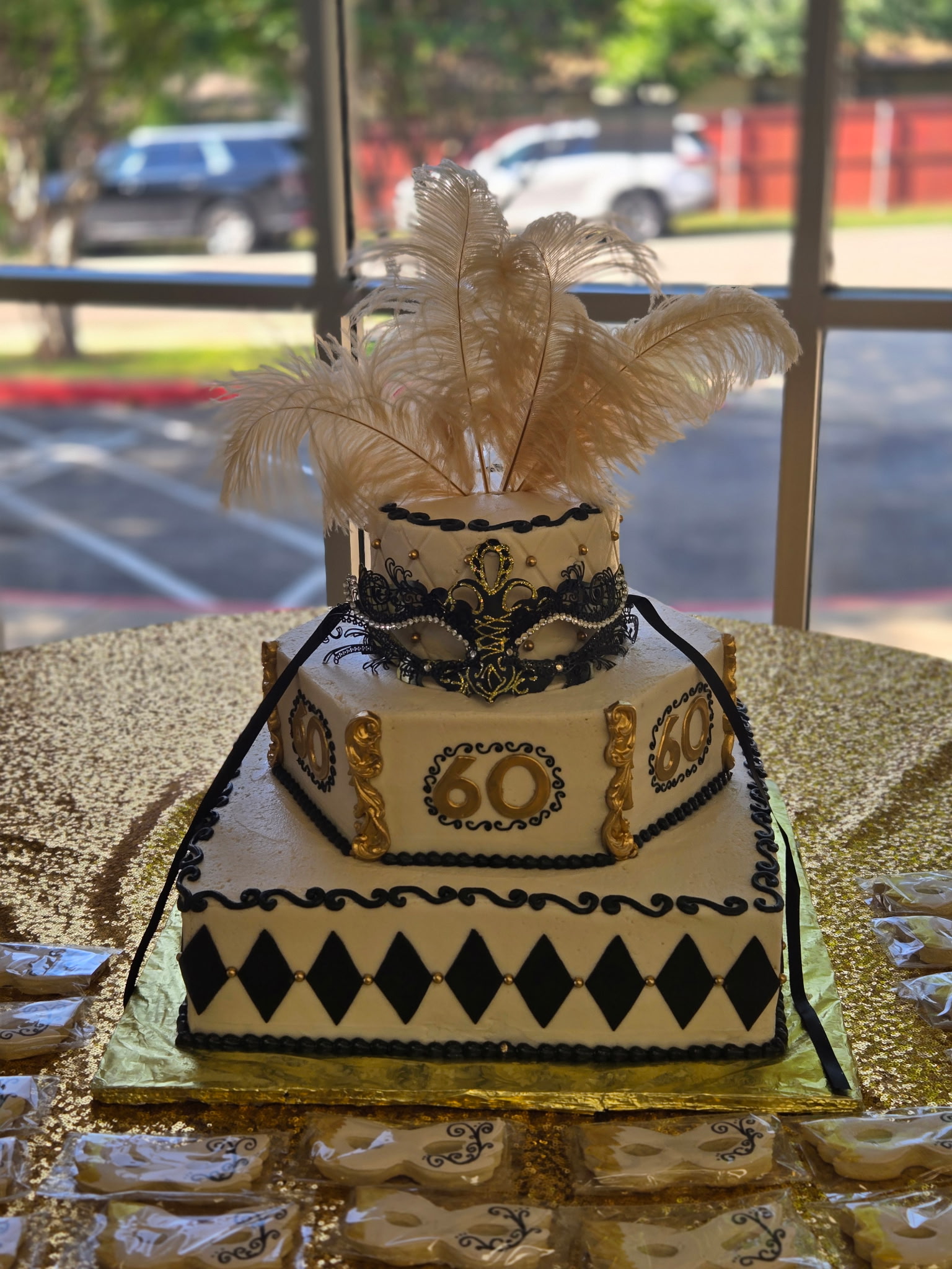 A dramatic black-and-gold masquerade-themed birthday cake with hand-piped detail and feather topper