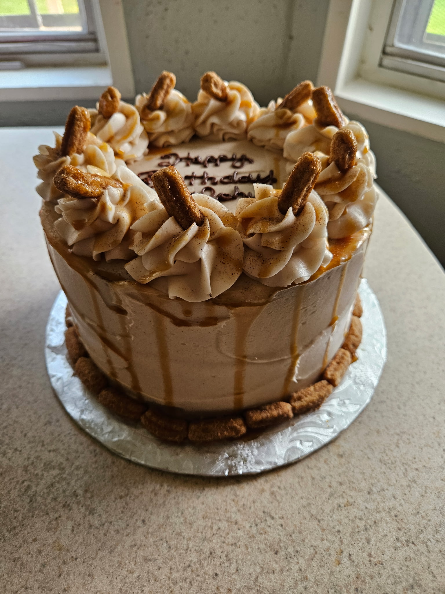 A cinnamon drip cake topped with churros and dulce de leche